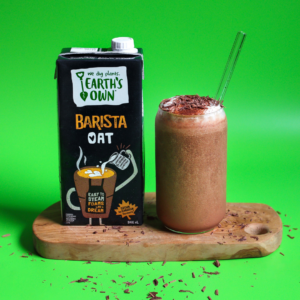 frozen mexican hot chocolate made with oat barista. glass full with straw in it placed beside a carton of oat barista