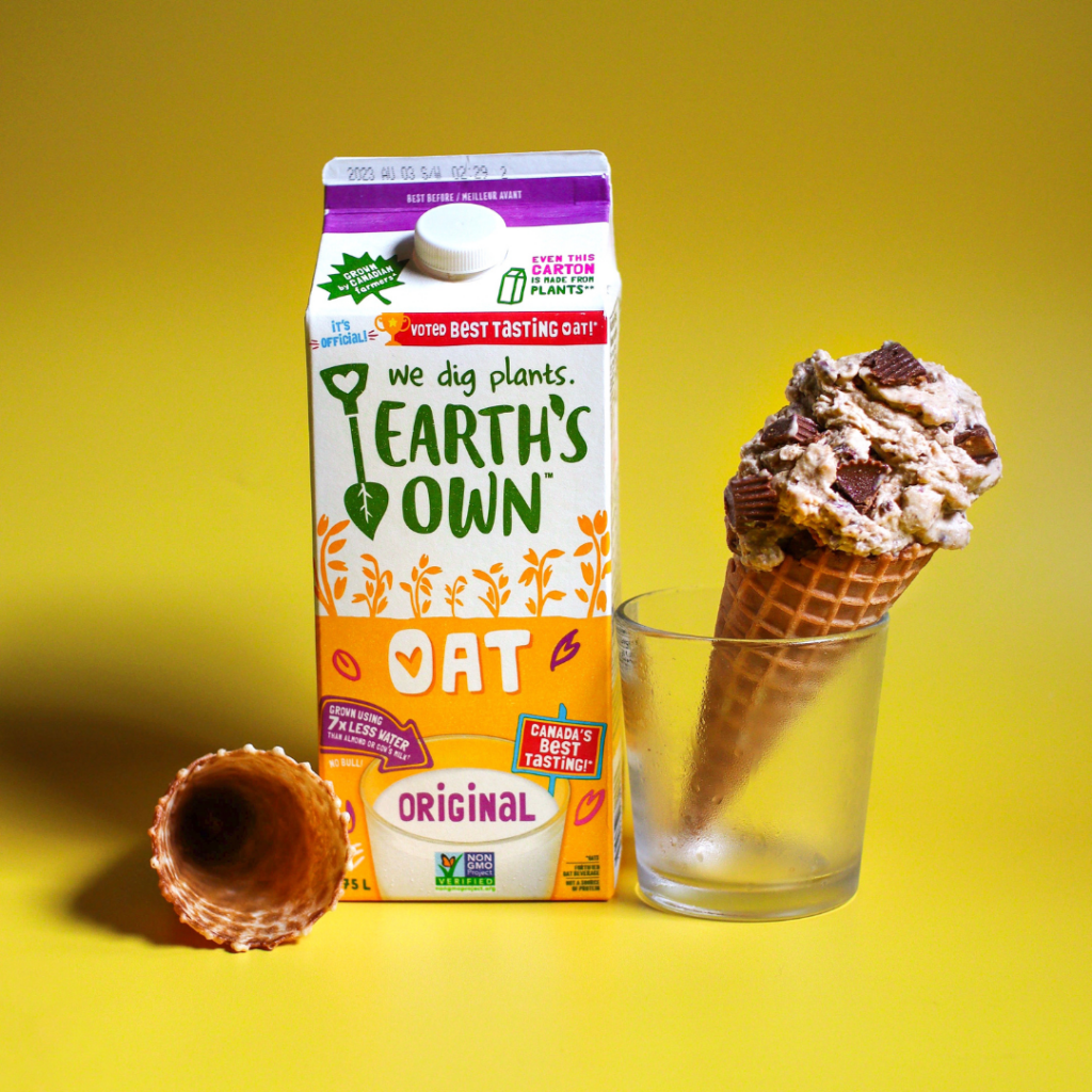 vegan peanut butter chocolate ice cream made with original oat milk. ice cream sits on cone in a glass jar with oat milk carton placed beside it infront of yellow background.