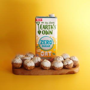 Pumpkin Cookie Dough Bites surround an Earth's Own Oat Zero Sugar Vanilla carton in front of a yellow background