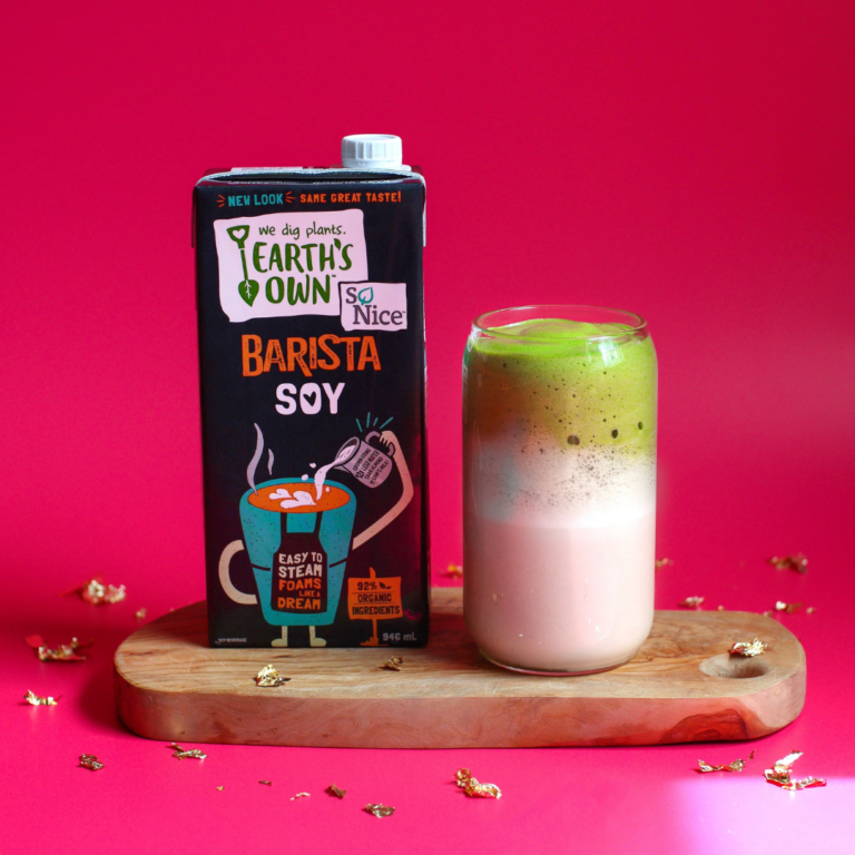 Soy Barista Matcha Dalgona. Soy barista carton sitting next to latte in glass. In front of bright pink backdrop.