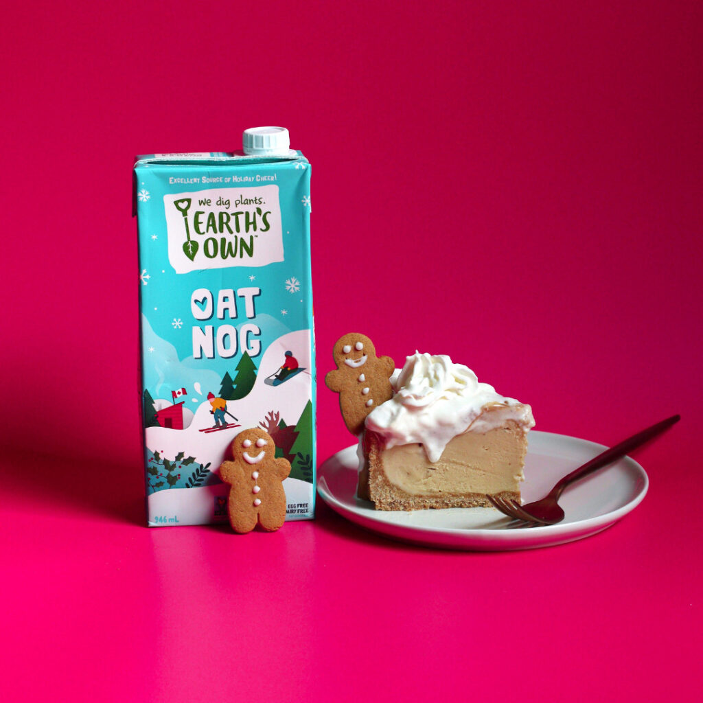 Oat nog cheesecake topped with small gingerbread men sat beside a carton of oat nog