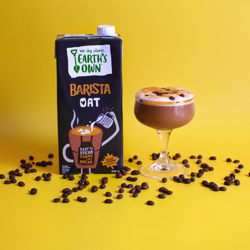 Espresso Martini Mocktail made with Earth's Own Oat Barista. Photo of Espresso Martini Mocktail filled in glassed topped with coffee beans, placed beside a carton of Oat Barista infront of a yellow background.